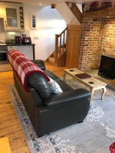 a living room with a leather couch and a table at Inglenook Cottage in Padstow