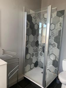 La salle de bains est pourvue d'une douche avec une porte en verre. dans l'établissement Aux portes des iles, à Saint-Just