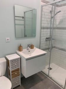 La salle de bains blanche est pourvue d'un lavabo et d'une douche. dans l'établissement Aux portes des iles, à Saint-Just