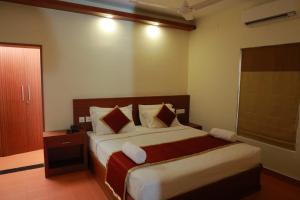 a hotel room with a bed and a window at Pearlspot Hotel in Kumarakom