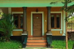 una casa con due colonne e una porta in legno di Pearlspot Hotel a Kumarakom