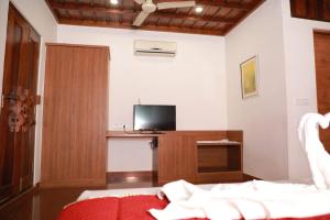 1 dormitorio con 1 cama y escritorio con TV en Pearlspot Hotel, en Kumarakom