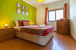 a bedroom with a bed with green walls and a window at Formosa View in Faro