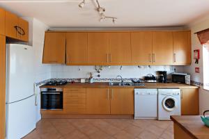 a kitchen with wooden cabinets and a washer and dryer at Formosa View in Faro