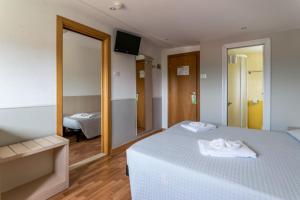 Schlafzimmer mit einem weißen Bett und einem Spiegel in der Unterkunft Hotel Stresa in Rimini