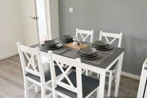 uma mesa de jantar com cadeiras brancas e uma mesa preta com pratos pretos em Kingfisher House by Blue Skies Stays em Stockton-on-Tees