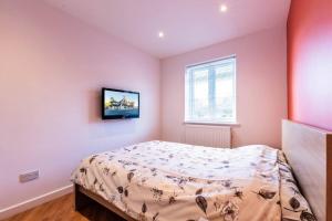a bedroom with a bed and a tv on the wall at Comfy Apartment 16 Easy access to Central London in Tadworth