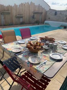 una mesa con una cesta de comida junto a una piscina en Aux portes des iles, en Saint-Just
