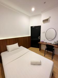 a bedroom with a bed and a mirror and a desk at Gemilang Hotel in Kota Kinabalu