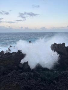 una ola chocando en las rocas en el océano en Villa Cap Méchant piscine chauffée avril à octobre, en Saint-Joseph