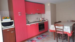 a kitchen with red cabinets and a small table at CASA DELLE PEONIE in Ruffano