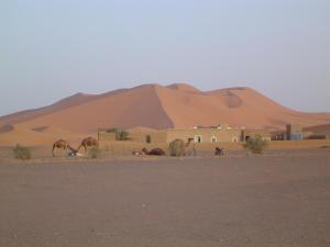 a village in the desert with a large sand mound at Chez Meriem in Merzouga