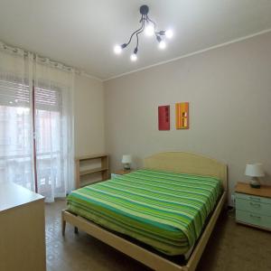 - une chambre dotée d'un lit avec des draps rayés verts et jaunes dans l'établissement Appartamento Viale della Repubblica, à Pietra Ligure