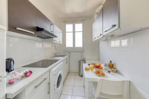 - une cuisine blanche avec un évier et un lave-vaisselle dans l'établissement Oh Parisien - 10 min Paris Montparnasse, à Vanves
