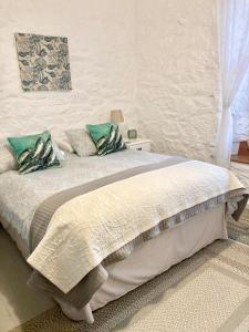 um quarto com uma grande cama branca com almofadas verdes em The Old Post House B&B em St Just