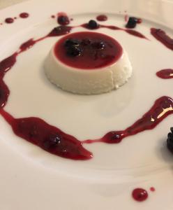 uma sobremesa com molho vermelho e mirtilos num prato branco em Hotel Comfort em Shëngjin