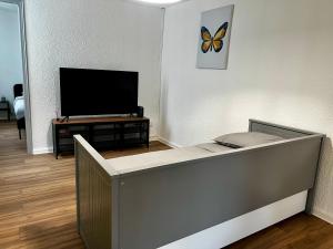 una sala de estar con TV y una mariposa en la pared en Appartements Rue des Jardins en Perpiñán
