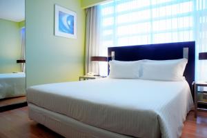 a bedroom with a large white bed with a large window at SANA Capitol Hotel in Lisbon