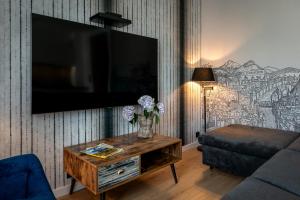 uma sala de estar com televisão e uma mesa com flores em Aparthotel InPoint Cracow G15 - Free Underground Parking em Cracóvia