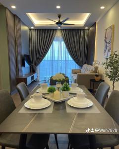 a dining room with a table and a living room at Nabiha Suites Bandar Baru Bangi in Bangi