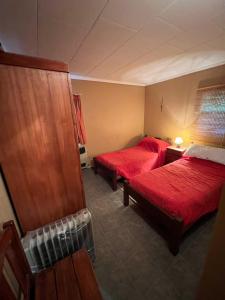 2 camas en una habitación de hotel con sábanas rojas en Casa de Montaña en La Angostura