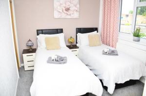 2 letti in una camera da letto con lenzuola bianche di 7SM Dreams Unlimited Serviced Accommodation- Stanwell-Staines-Heathrow a Stanwell