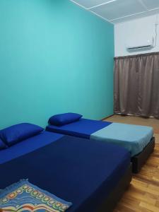 - 2 lits dans une chambre aux murs bleus dans l'établissement 4 Bedroom House Indera Mahkota 8 Kuantan Homestay, à Kuantan