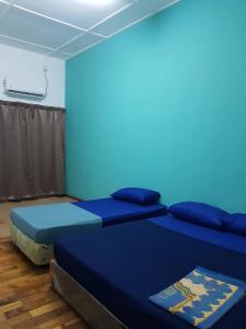 - 2 lits dans une chambre avec un mur bleu dans l'établissement 4 Bedroom House Indera Mahkota 8 Kuantan Homestay, à Kuantan