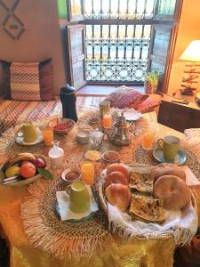a table with a breakfast of bread and orange juice at Maison d'hôtes IZZA in El Kelaa des Mgouna