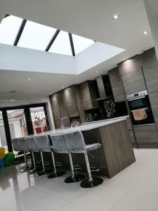 una cocina con barra con taburetes. en Grand 4 Bed 3 Bath House Chadwell Heath, Romford, London en Goodmayes