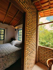 伦索伊斯Casa Lipe & Rafa Linda casa com árvores的卧室设有砖墙、床和窗户
