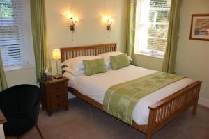 a bedroom with a bed and a chair and two windows at Trafalgar House in Torquay