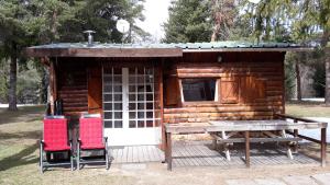eine Holzhütte mit 2 Stühlen und einem Tisch in der Unterkunft Cabane randonneur au camping in Camurac