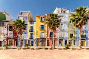 una fila de edificios coloridos con palmeras delante en Appartement Cala Merced El Campello, en El Campello