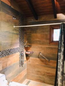 y baño con paredes de madera y ducha. en Cabaña de Montaña en San Martín de los Andes