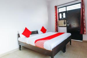 a bedroom with a bed with red pillows and a window at OYO Hindon Residency in Ghaziabad