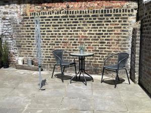 einen Tisch und Stühle vor einer Ziegelwand in der Unterkunft Mildmay Road Apartments in London