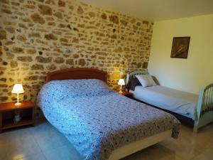 a bedroom with two beds and a stone wall at La Maison de Musique in Nohant-Vic