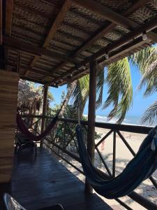 a porch with a hammock and the beach at HOSTAL Estrellas del tayrona playa in Santa Marta