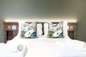 Cama con sábanas y almohadas blancas en The Pheasant Inn en Grange Over Sands