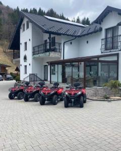 una fila de cuatro ATvs estacionados frente a un edificio en Pensiunea Paradisul Verde, en Moisei