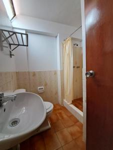 y baño con aseo, lavabo y ducha. en Hotel la casona, en Huaraz