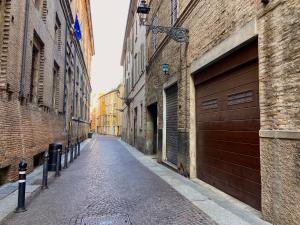 un callejón vacío con dos puertas de garaje y un edificio de ladrillo en Maison Sarraj Affittacamere, en Parma