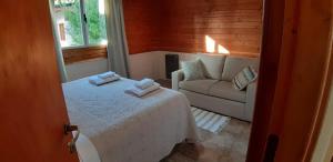 Habitación pequeña con cama y sofá en Cabaña Los Alamos en Dina Huapi