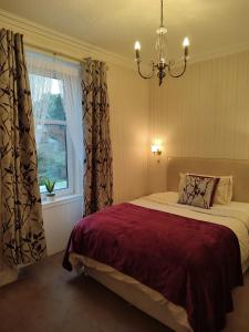 a bedroom with a bed with a chandelier and a window at Dunallan Guest House in Perth