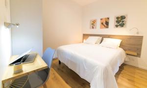 a bedroom with a bed and a desk with a laptop at La Dolive - Locationtournus in Tournus