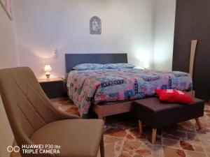 a bedroom with a bed and a chair and a table at Casa Vacanza Nonna Enza in Marsala