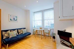 Calabria 2 - Cosy apartment في لندن: غرفة معيشة مع أريكة زرقاء وطاولة