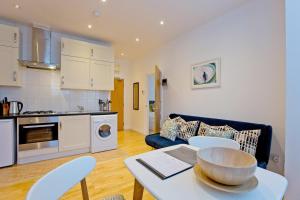 Calabria 2 - Cosy apartment في لندن: مطبخ وغرفة معيشة مع طاولة وكراسي