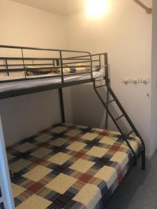 a bunk bed with a checkered blanket on the bottom bunk at Le Villergeois 5 pers très proche mer in Villers-sur-Mer